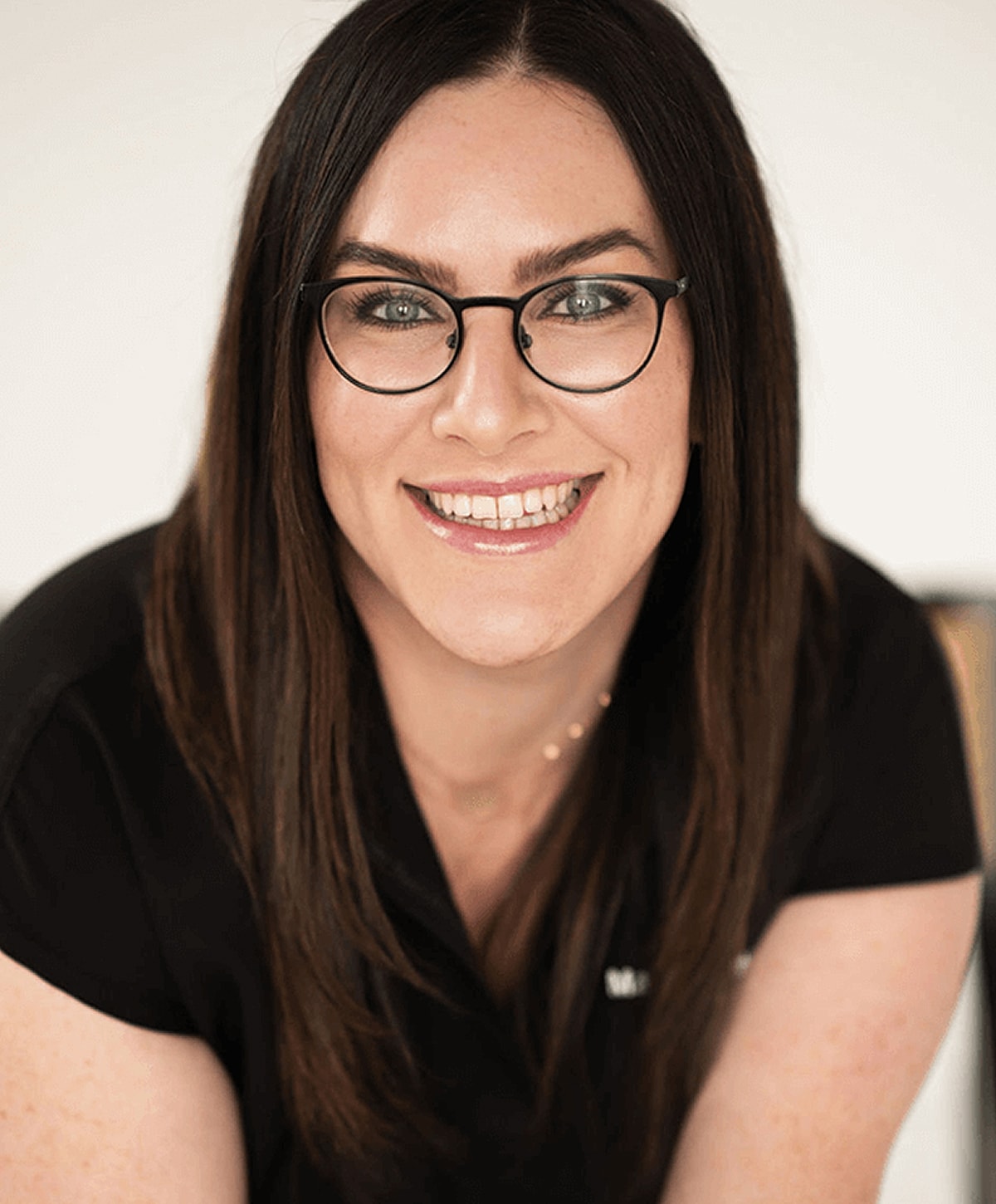 Smiling woman with long hair and glasses.