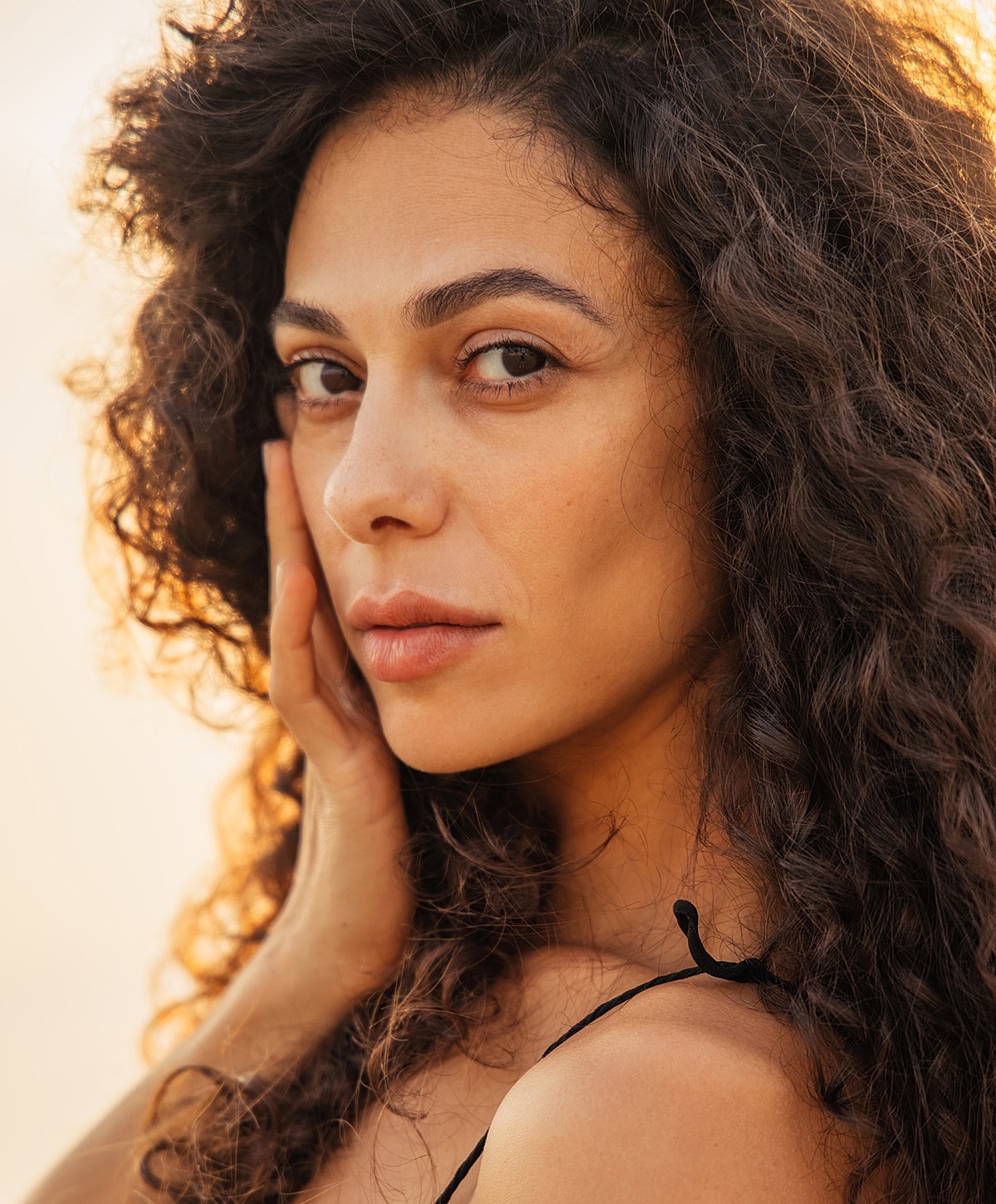Close-up of woman with curly hair and natural makeup.
