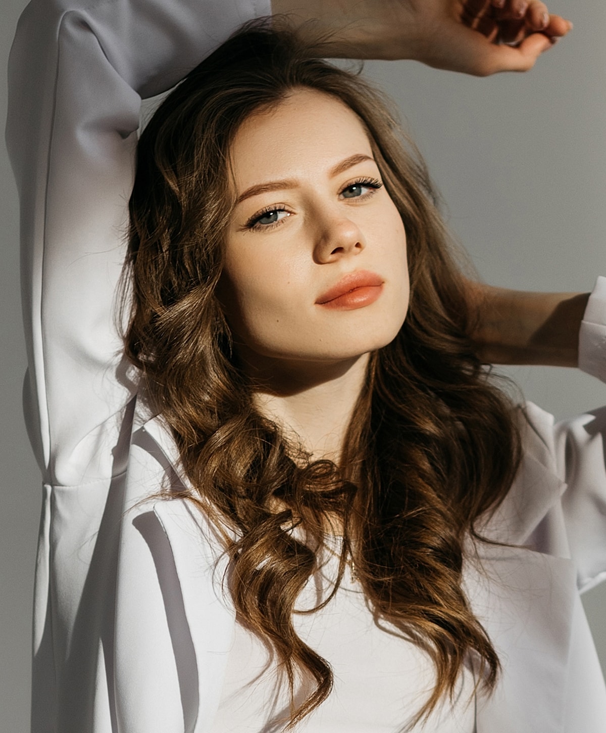 Model posing with arms raised, soft lighting.