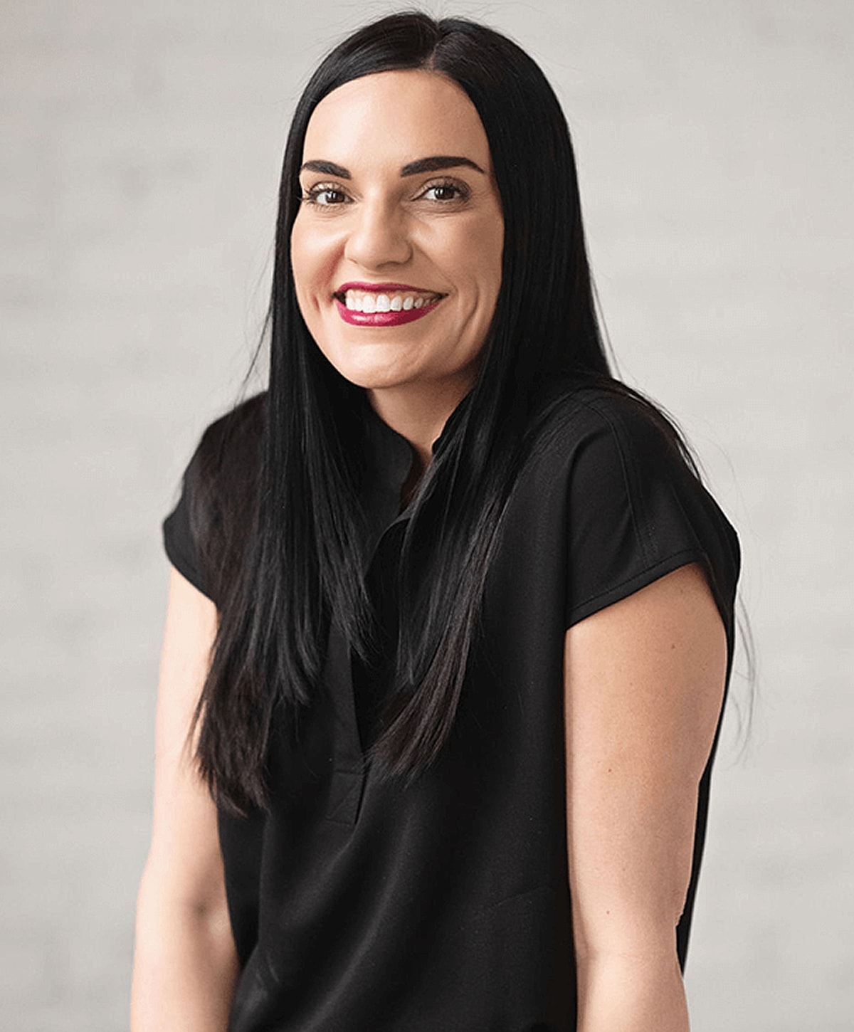 Smiling woman with long dark hair in black top.