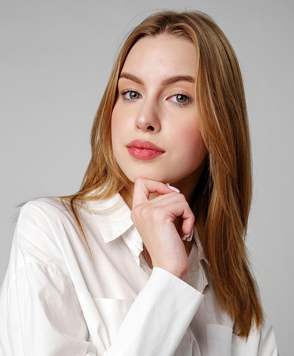 Woman in white shirt, thoughtful expression, casual pose.