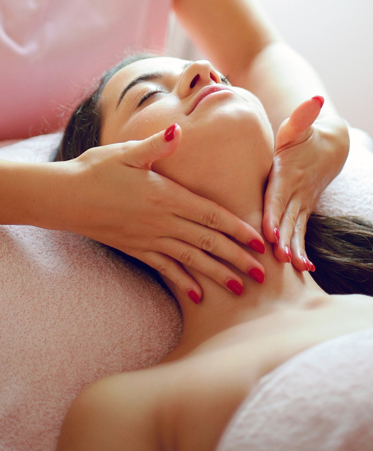 Woman receiving a facial massage in spa setting.