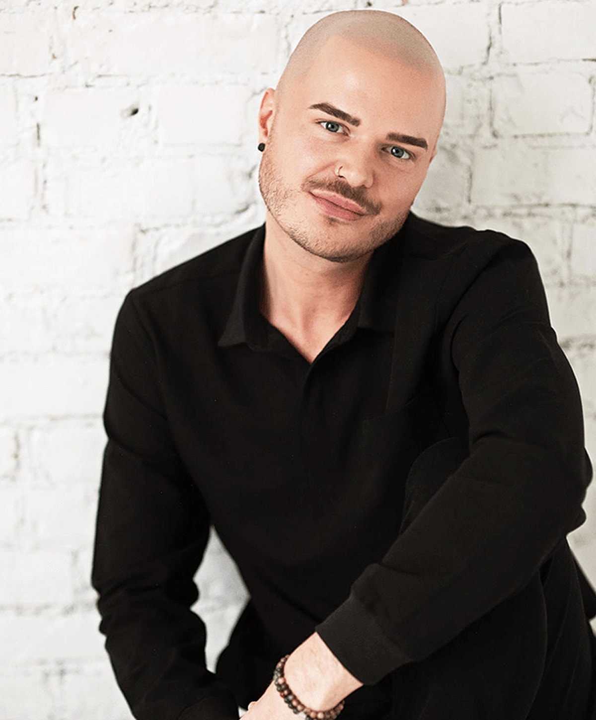 Person with shaved head and stylish black outfit.