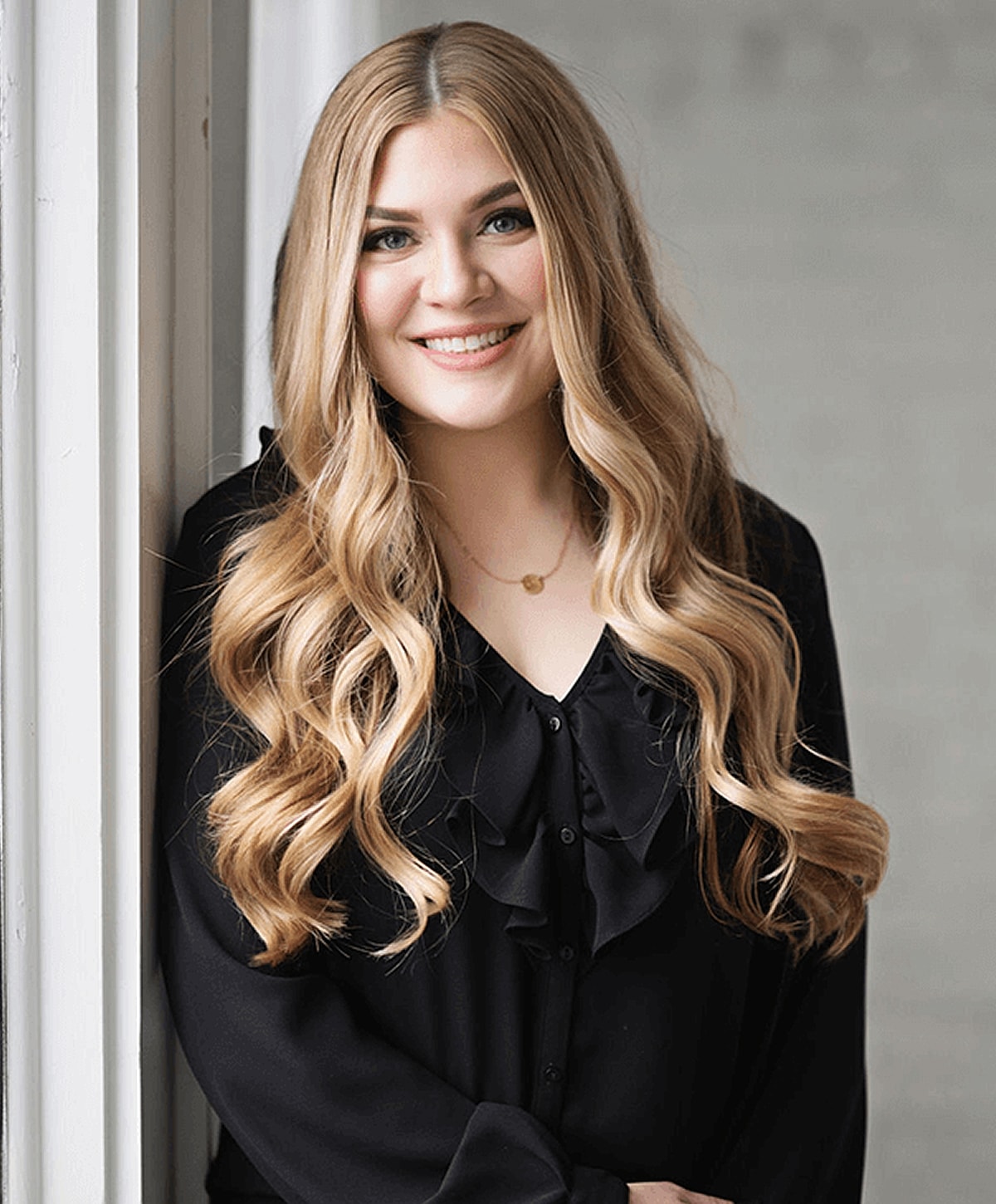 Smiling woman with long wavy hair in black shirt.