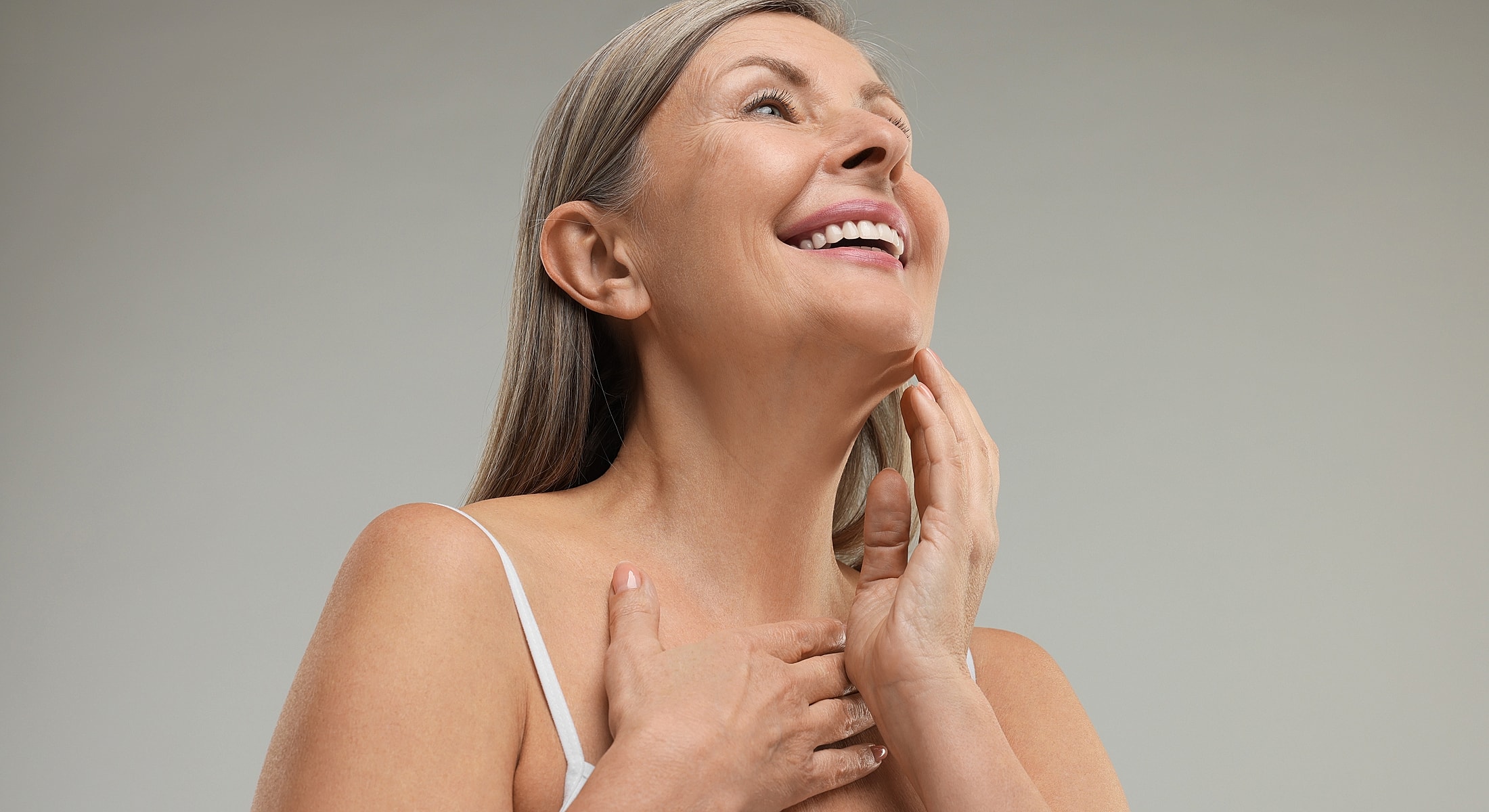 Smiling woman with gray hair, soft lighting.